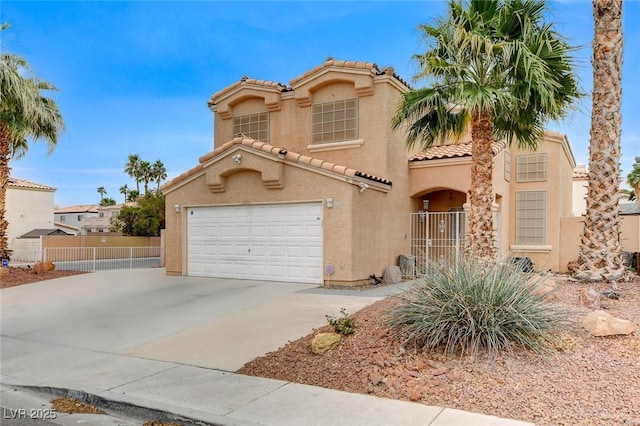 mediterranean / spanish home featuring stucco siding, driveway, a tile roof, fence, and a garage