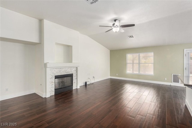 unfurnished living room with a stone fireplace, dark wood-type flooring, a ceiling fan, and vaulted ceiling