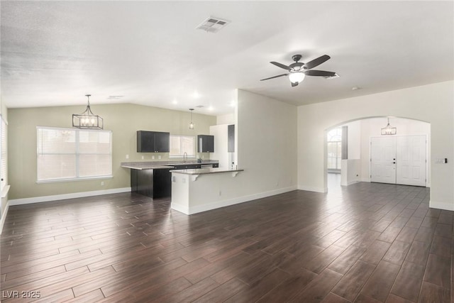 unfurnished living room featuring visible vents, arched walkways, a healthy amount of sunlight, and dark wood finished floors