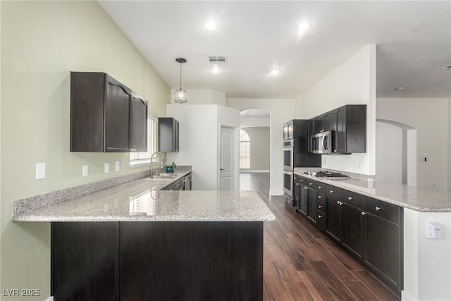 kitchen with visible vents, a peninsula, arched walkways, stainless steel appliances, and a sink