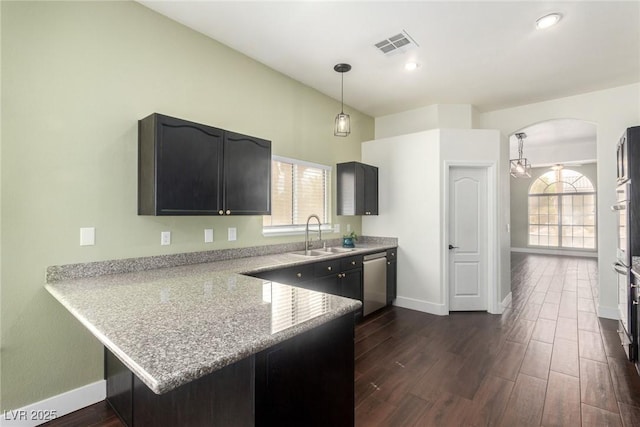 kitchen featuring visible vents, a sink, a peninsula, arched walkways, and stainless steel dishwasher