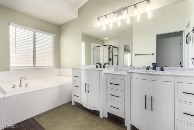 bathroom featuring two vanities, wood finished floors, a stall shower, and a sink