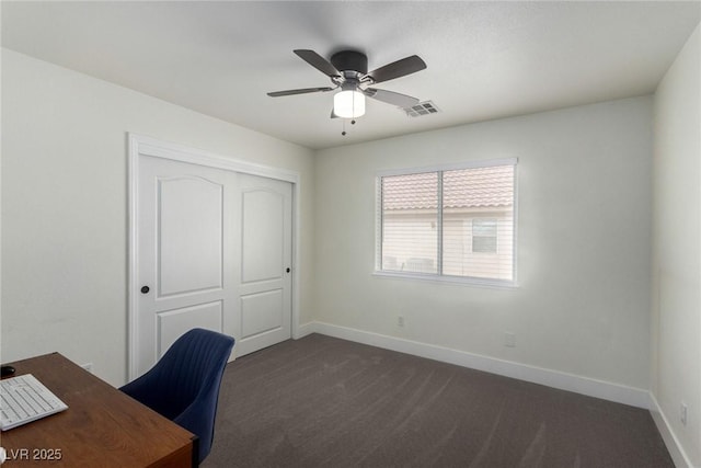 unfurnished office featuring baseboards, visible vents, dark carpet, and ceiling fan