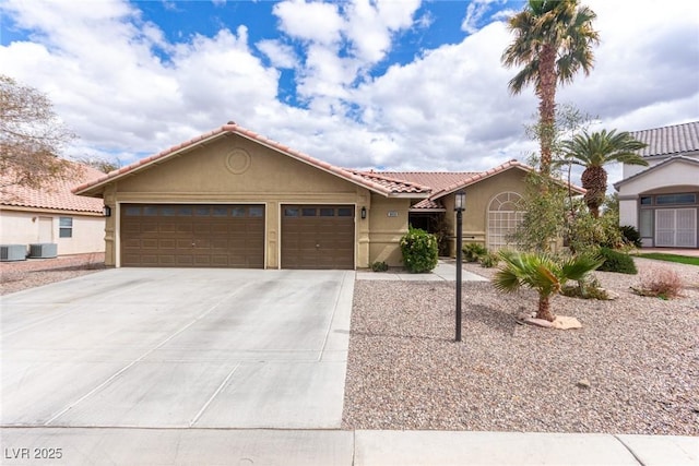 view of front of house with stucco siding, a tiled roof, concrete driveway, and a garage