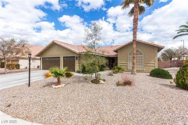 view of front of home featuring a tiled roof, stucco siding, an attached garage, and driveway