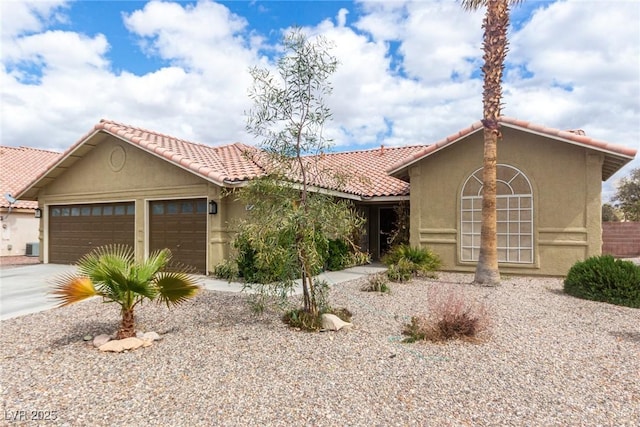 view of front of home with stucco siding, a garage, driveway, and a tile roof