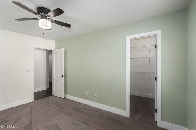 unfurnished bedroom with a spacious closet, a closet, baseboards, and carpet