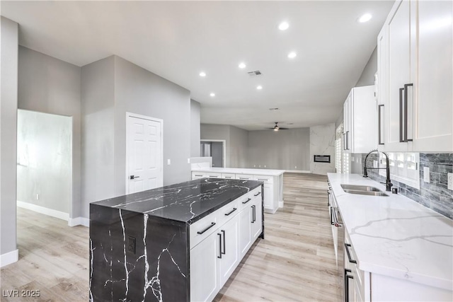 kitchen featuring visible vents, a sink, a kitchen island, light wood finished floors, and ceiling fan