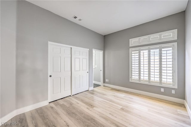 unfurnished bedroom with visible vents, baseboards, a closet, and wood finished floors