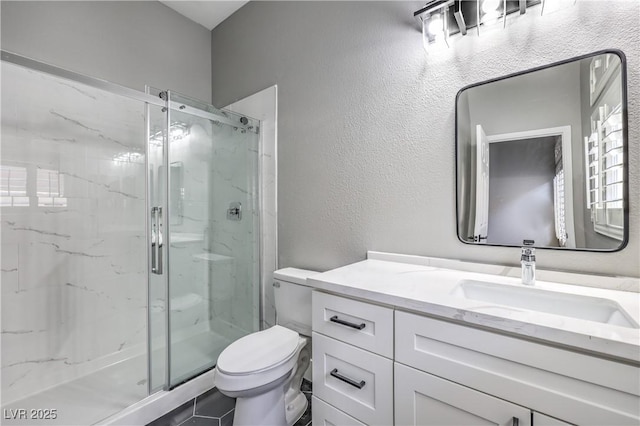 bathroom with a marble finish shower, toilet, vanity, and a textured wall