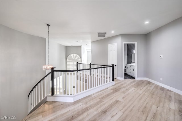 empty room featuring visible vents, recessed lighting, light wood finished floors, baseboards, and a chandelier