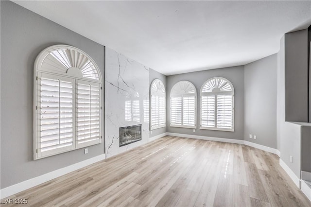 unfurnished living room with wood finished floors, baseboards, and a premium fireplace