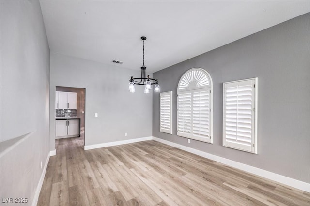 unfurnished dining area featuring a chandelier, visible vents, light wood-style flooring, and baseboards