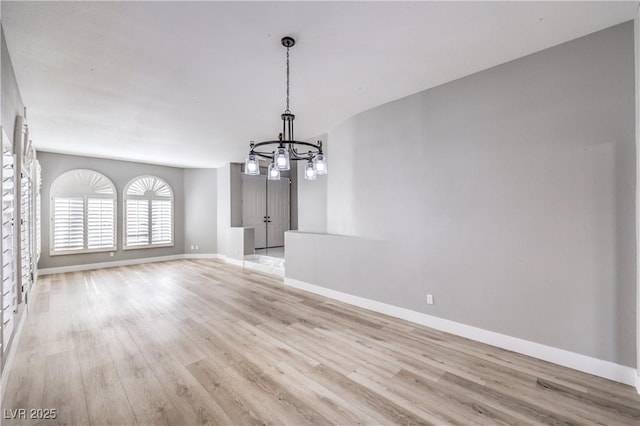 unfurnished dining area with baseboards, a chandelier, and light wood finished floors