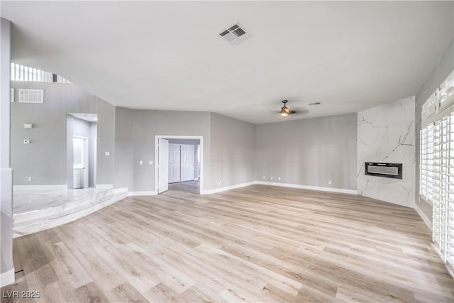 unfurnished living room with a ceiling fan, light wood-style floors, visible vents, and a premium fireplace