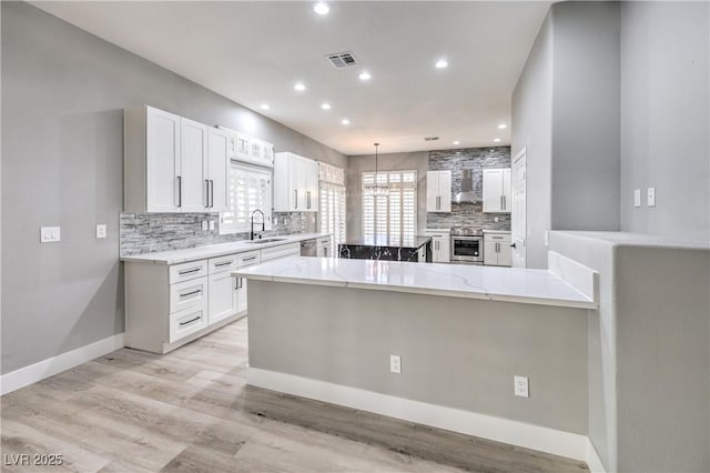 8864 La Manga Ave, Las Vegas, NV 89147 - kitchen with light stone counters, stainless steel appliances, backsplash, visible vents, and white cabinetry