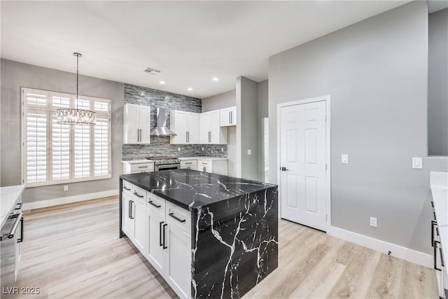 8864 La Manga Ave, Las Vegas, NV 89147 - kitchen with wall chimney exhaust hood, light wood-type flooring, a notable chandelier, decorative backsplash, and stainless steel gas stove