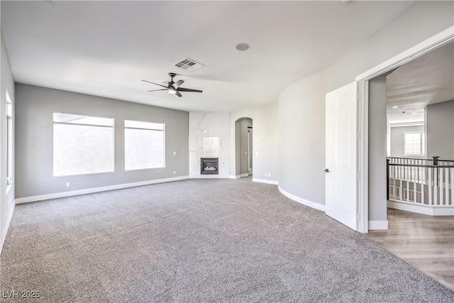 8864 La Manga Ave, Las Vegas, NV 89147 - unfurnished living room featuring ceiling fan, arched walkways, baseboards, carpet flooring, and visible vents