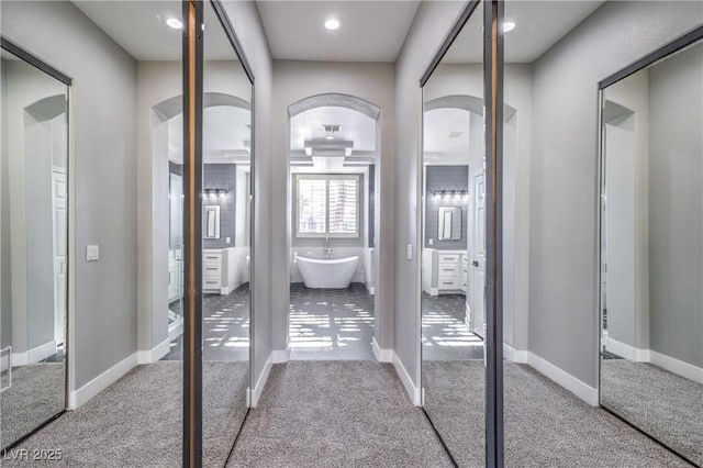 interior space featuring baseboards, arched walkways, and carpet floors