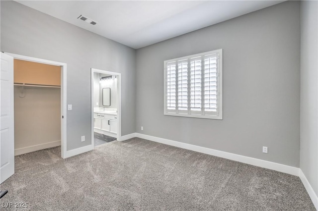 unfurnished bedroom with baseboards, visible vents, a spacious closet, a closet, and carpet flooring