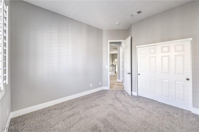 unfurnished bedroom featuring visible vents, carpet floors, baseboards, and a closet