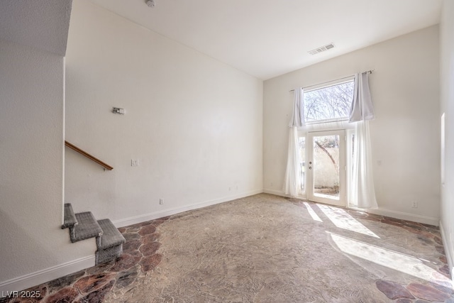 unfurnished living room featuring visible vents, baseboards, a towering ceiling, and stairs