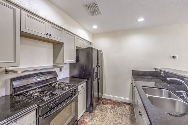 kitchen with visible vents, baseboards, dark stone counters, black appliances, and a sink