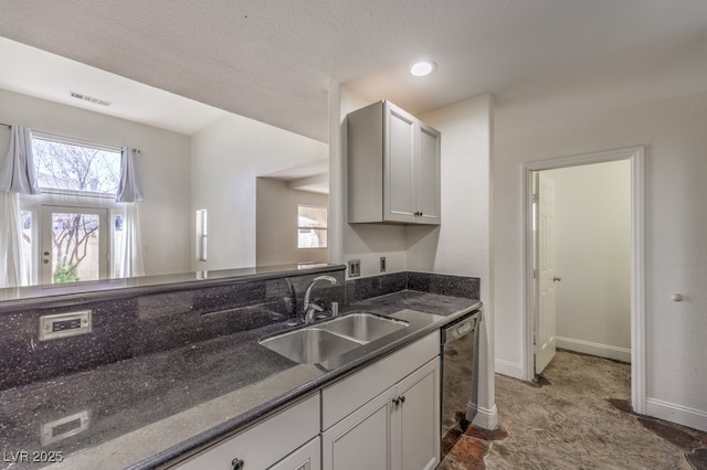 kitchen with plenty of natural light, dishwasher, dark stone counters, and a sink