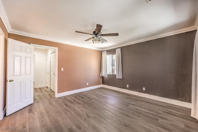 spare room featuring crown molding, wood finished floors, baseboards, and ceiling fan