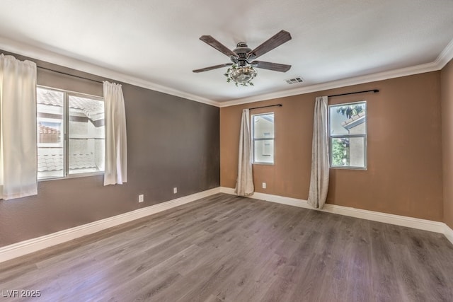 unfurnished room with a ceiling fan, baseboards, wood finished floors, visible vents, and ornamental molding