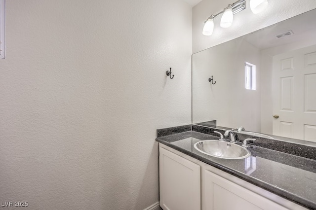 bathroom with vanity, a textured wall, and visible vents