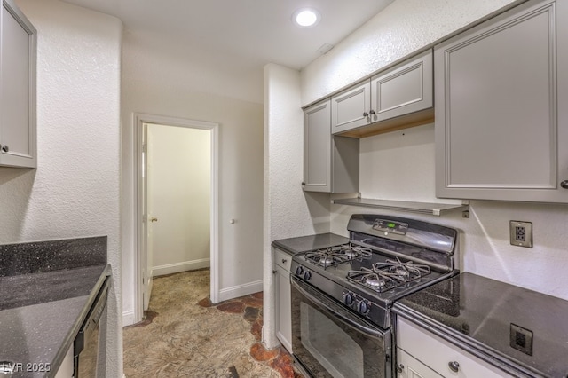 kitchen featuring black gas range oven, baseboards, dark stone counters, gray cabinets, and stone finish floor