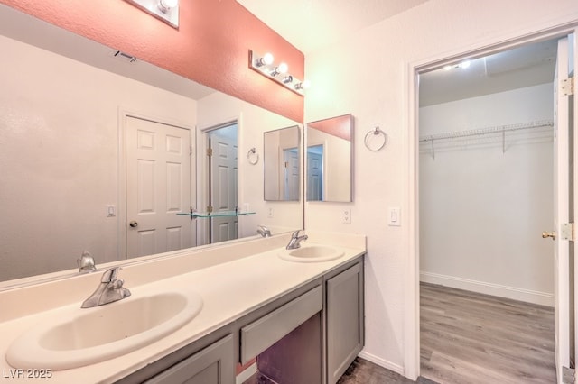 bathroom with double vanity, visible vents, baseboards, and a sink