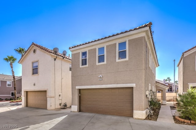 view of front facade featuring concrete driveway, an attached garage, fence, and stucco siding