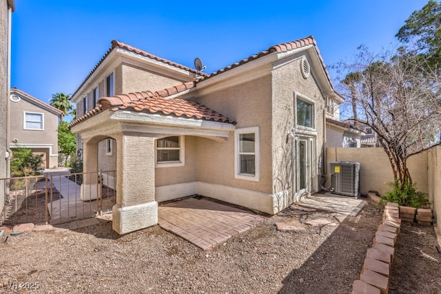 rear view of property featuring a patio, fence, central AC, stucco siding, and a tile roof