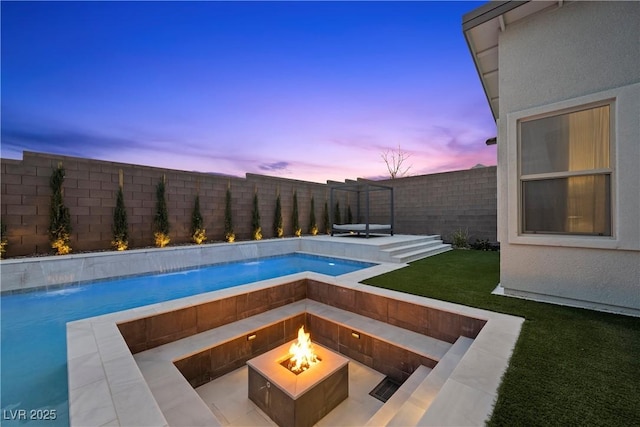 pool at dusk featuring a fenced in pool, a fenced backyard, a lawn, and an outdoor fire pit