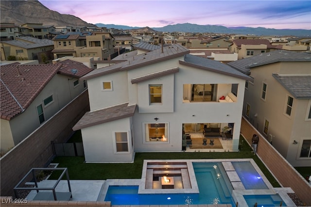 back of house at dusk with a patio area, a yard, a mountain view, and a fenced backyard