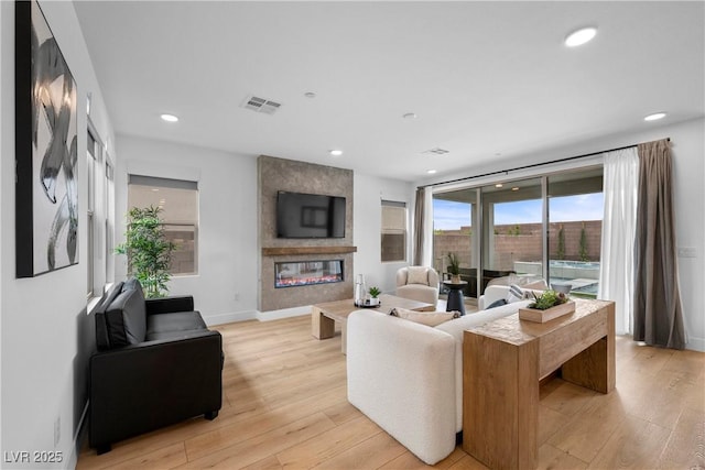 living area featuring visible vents, a large fireplace, baseboards, recessed lighting, and light wood-style floors