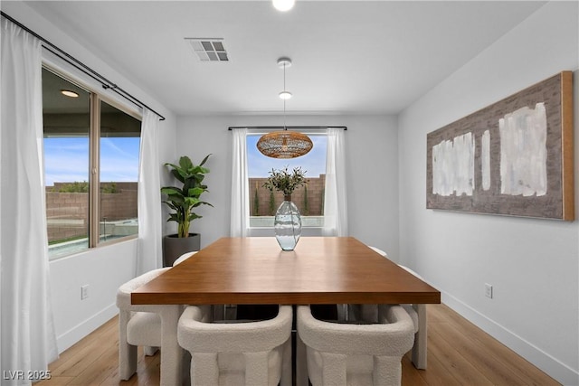 dining space featuring baseboards, visible vents, and light wood finished floors