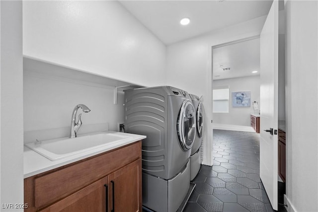 laundry area with dark tile patterned floors, laundry area, recessed lighting, washer and dryer, and a sink