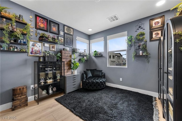 living area with visible vents, baseboards, and wood finished floors