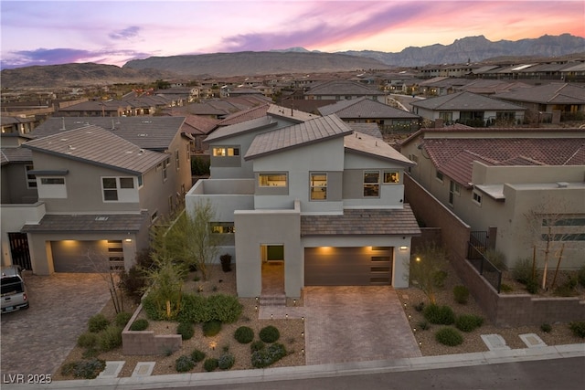 view of front of home with stucco siding, a residential view, an attached garage, and decorative driveway