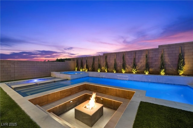 pool at dusk featuring a pool with connected hot tub, an outdoor fire pit, and a fenced backyard