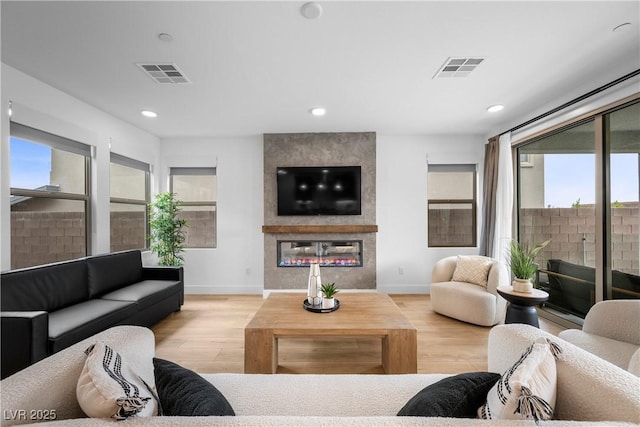 living area featuring visible vents, wood finished floors, and a fireplace