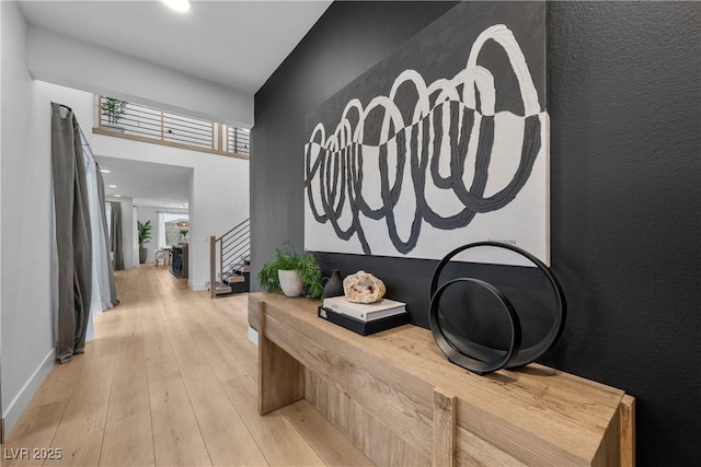 hall featuring stairway, light wood-style floors, and baseboards