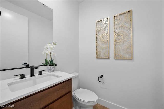 half bath featuring toilet, vanity, and baseboards