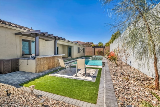 exterior space featuring a patio, a pool with connected hot tub, exterior kitchen, and a fenced backyard