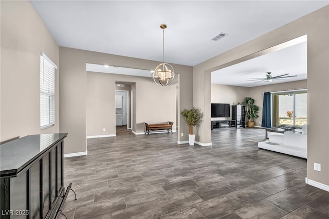 unfurnished dining area featuring ceiling fan with notable chandelier, baseboards, and visible vents