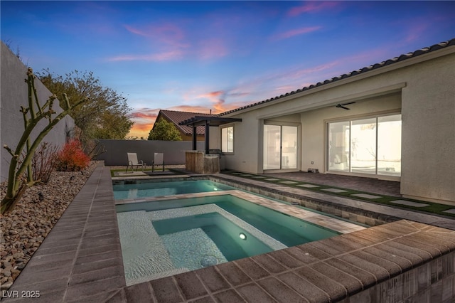 pool at dusk with an in ground hot tub, a fenced backyard, a fenced in pool, and a patio area