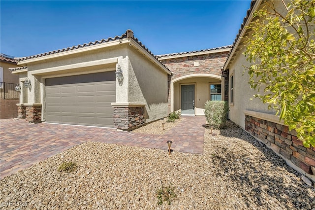 mediterranean / spanish-style house featuring decorative driveway, stone siding, an attached garage, and stucco siding